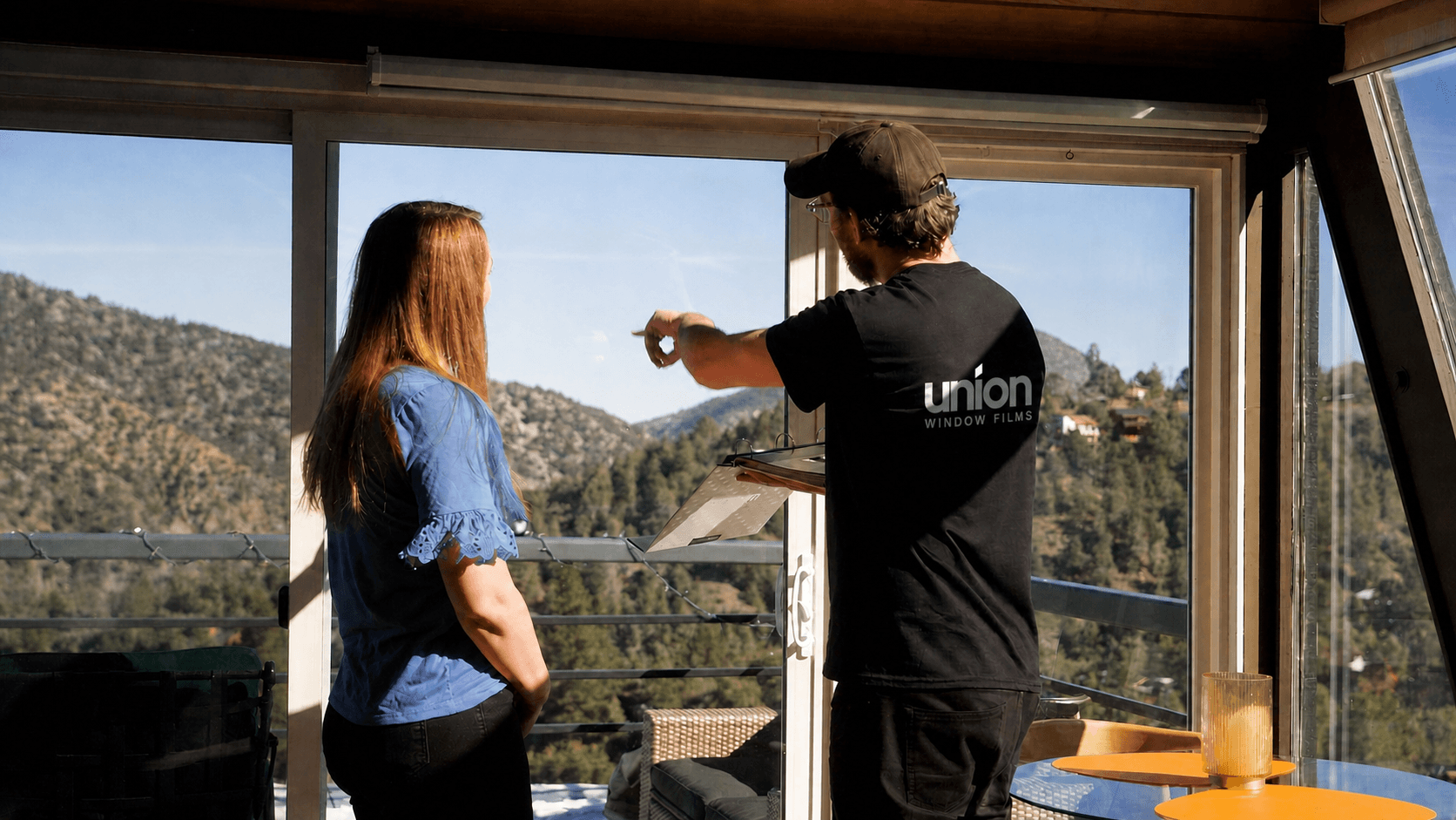 Union dealer pointing at a large residential window while the homeowner wears a blue shirt