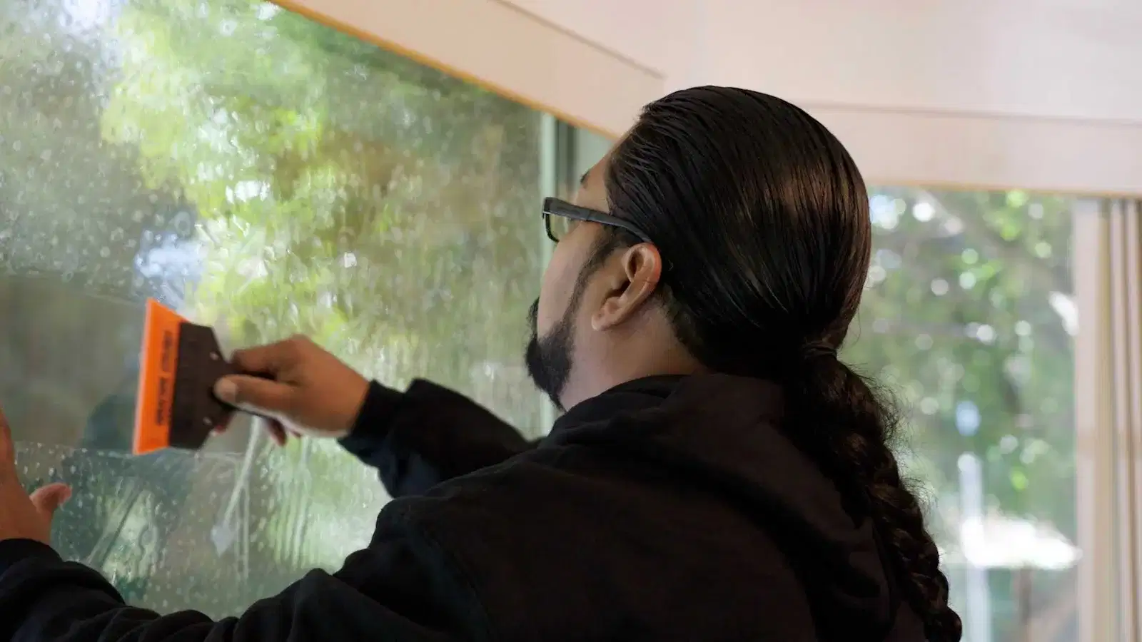Union installer squeegeeing architectural window film on residential glass