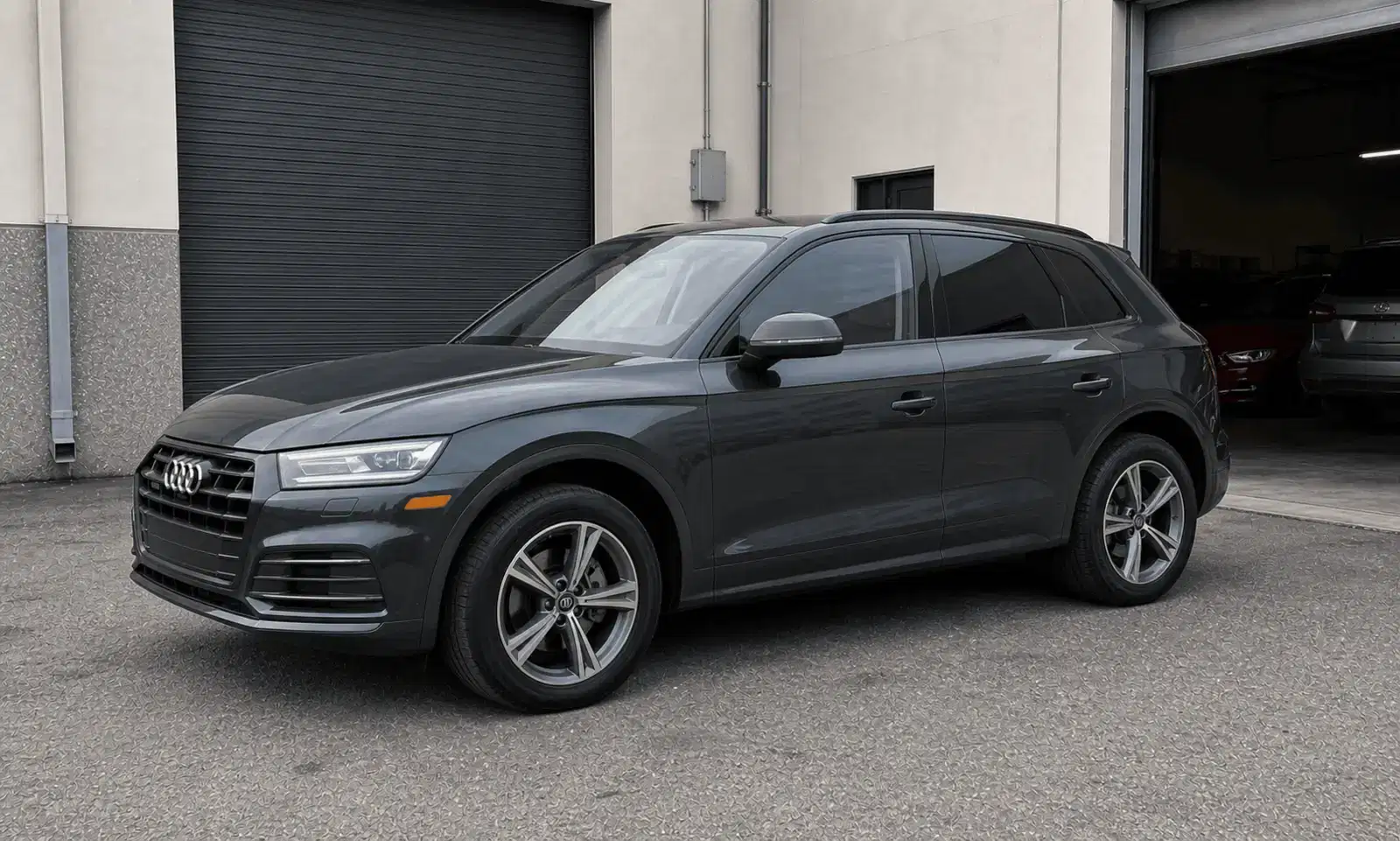 Graphite Audi Q5 with medium dark window tint outside a tint workshop