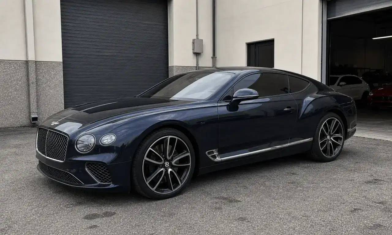 Navy Bentley Continental GT with premium window tint outside a tint workshop
