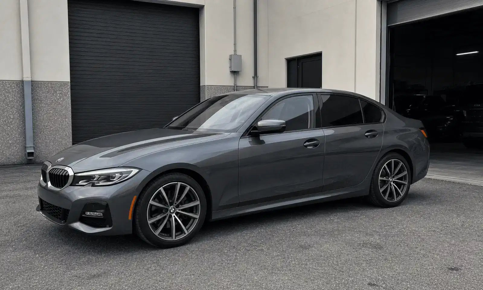 Mineral grey BMW 3 Series with tinted windows outside a tint workshop