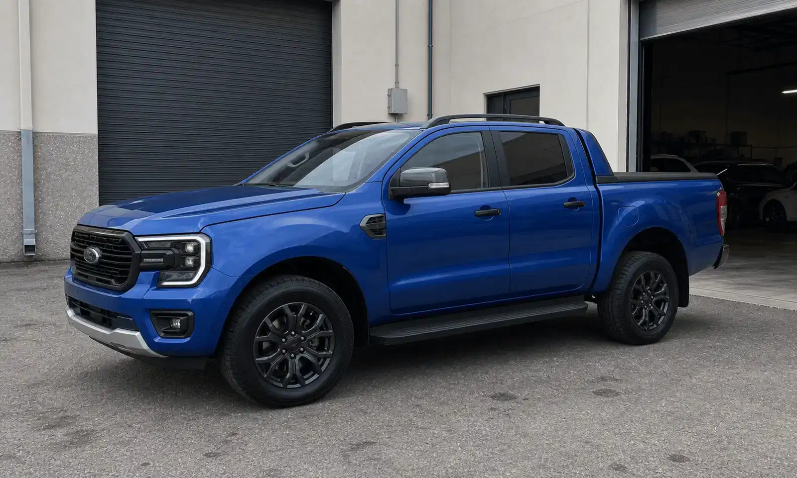 Blue Ford Ranger with clear windshield and graduated side tint outside a tint workshop