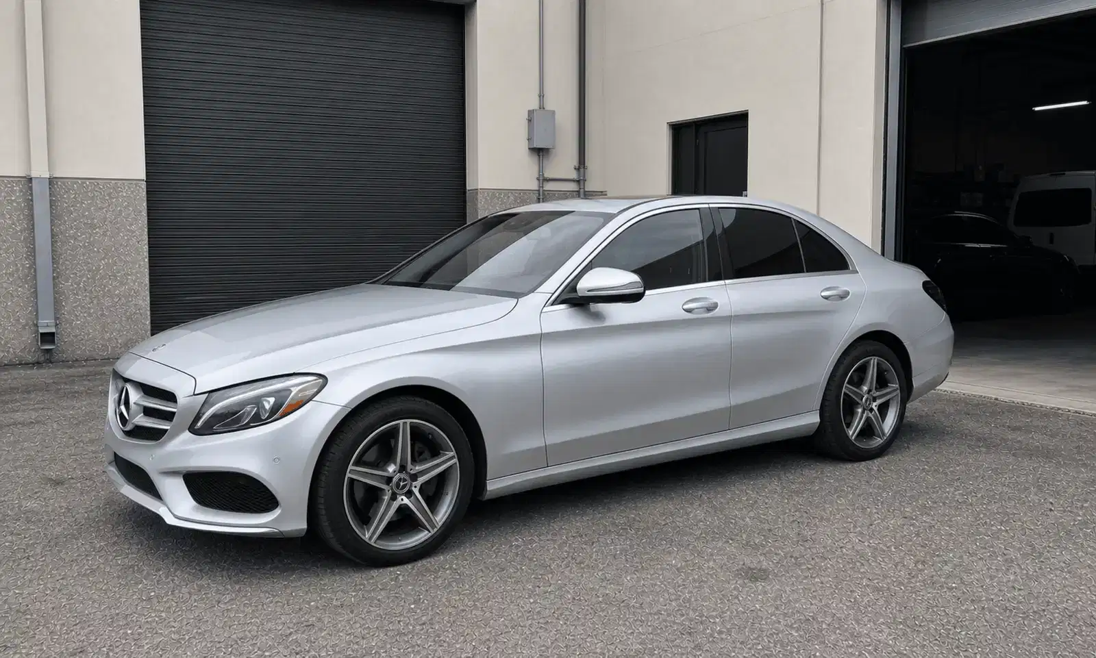 Silver Mercedes C-Class with tinted windows outside a tint workshop