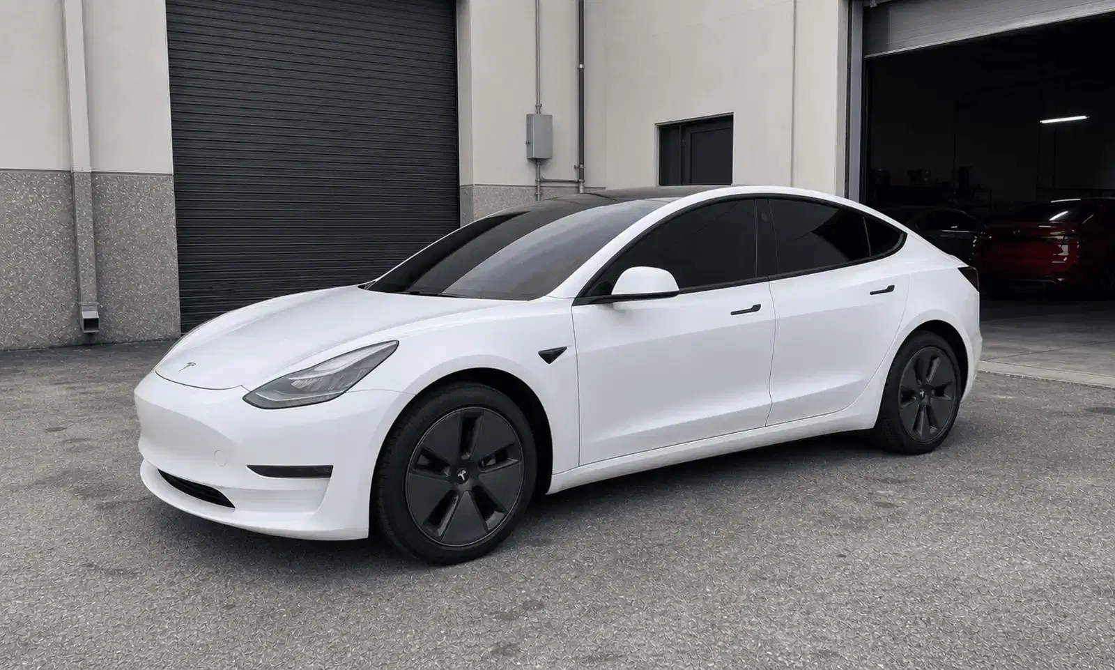 White Tesla Model 3 with tinted windows outside a tint workshop