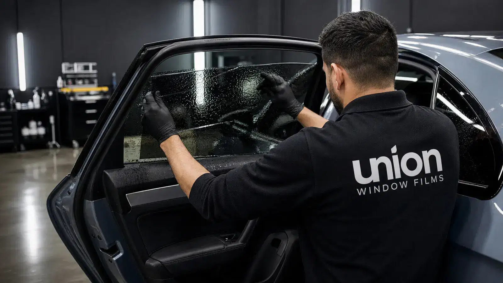 Union Window Films installer fitting tint film on a sedan door glass